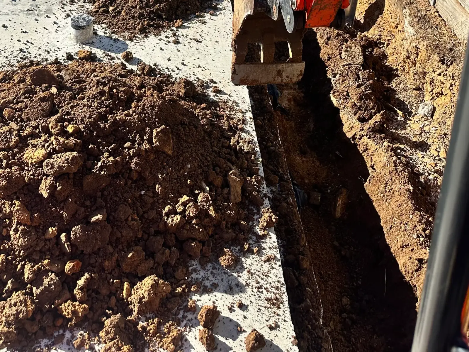 Excavator lowering a large stormwater chamber into an excavated trench