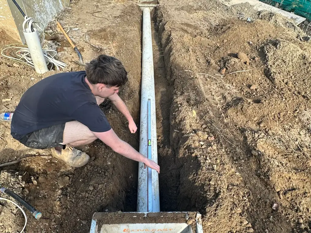 High-pressure jetter hose reel feeding into an open sewer inspection point in a back yard