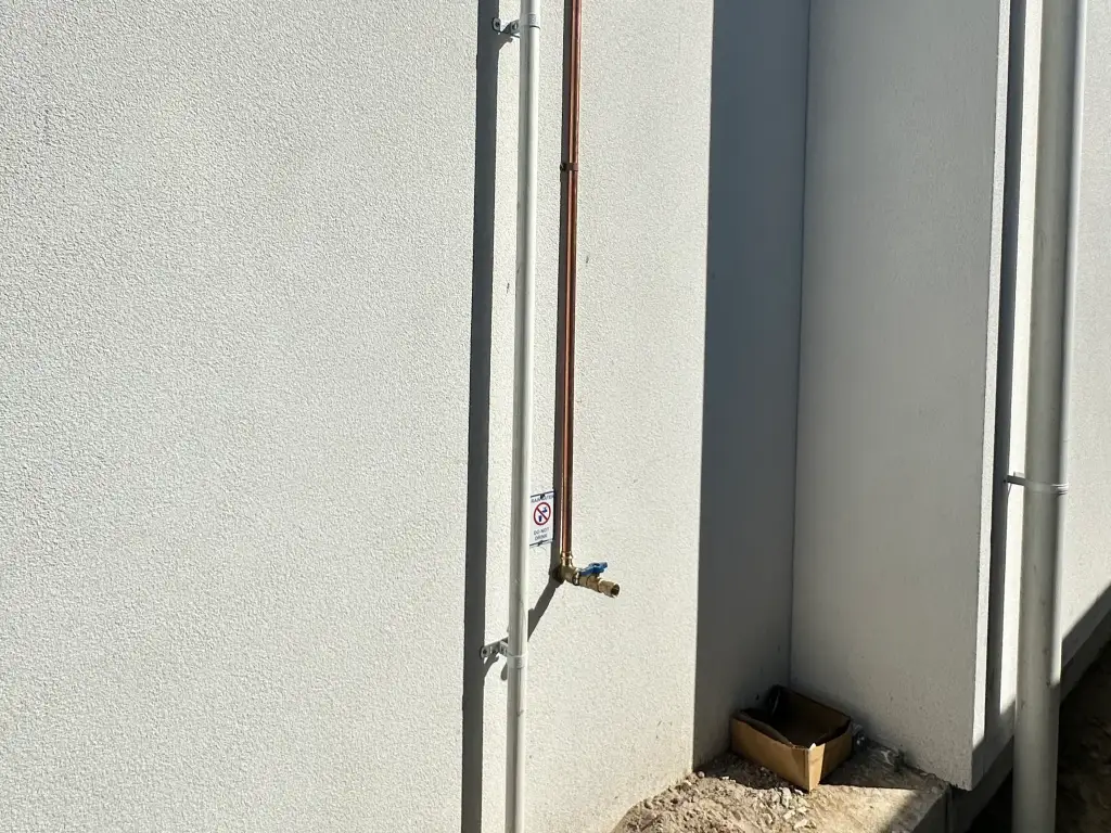 Gloved hands pressure testing a new copper gas line with a manometer gauge
